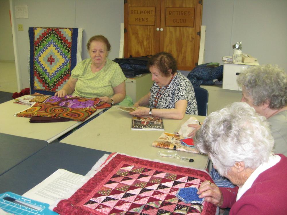 During a quilting group at the Belmont Senior Center, Eleanor Pinnone (left), 80, and Liz Malsky, 72, talk about proposed new laws that would require more testing for elderly drivers. (Sacha Pfeiffer/WBUR)
