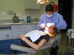 Dentist David Samuels works on Cathy Mazzuchi's pearly whites. Mass. dentists have been seeing an increase in stress-related tooth injuries during this economic downturn. (Curt Nickisch/WBUR)