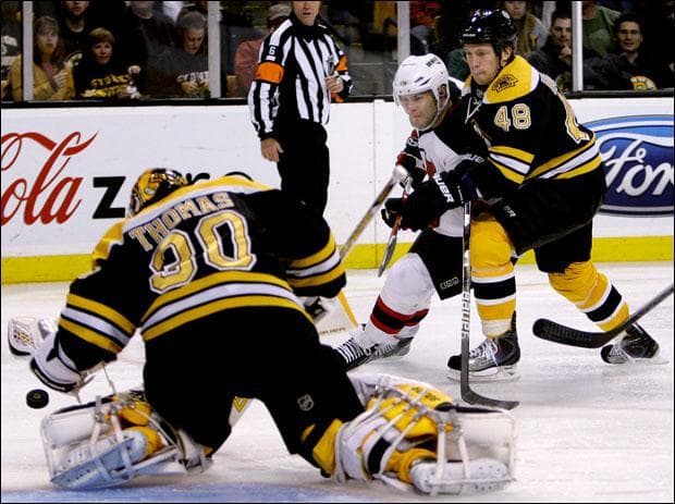 Goalie Tim Thomas makes a save as Boston Bruins defenseman Matt Hunwick checks New Jersey Devils center Rod Pelley on Thursday. (Charles Krupa/AP)