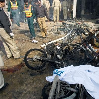 Pakistani rescue workers and police officers examine the site of bomb explosion outside a bank in Rawalpindi. (Anjum Naveed/AP)