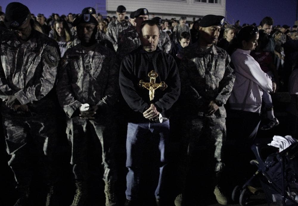 One carrying a cross, mourners pray during a vigil in Fort Hood, Texas on Friday,  in the wake of Thursday's shootings that killed 13 people on the base. (AP Photo/LM Otero)