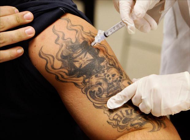 Firefighter and Paramedic Chuck Rivanis is injected with the swine flu vaccine at Winchester Town Hall last month. (Charles Krupa/AP)
