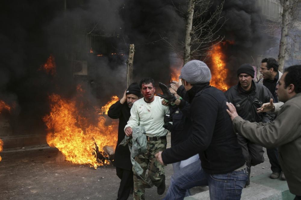 This photo, obtained by the AP outside Iran shows an Iranian police officer, center with white shirt, is protected and is taken away by people after being beaten by protestors during anti-government protest in Tehran, Sunday. (AP Photo)