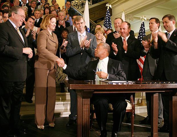 Massachusetts Gov. Deval Patrick, seated right, shakes Senate President Therese Murray's hand after signing an ethics bill on July 1, 2009, in Boston. Among state officials watching are Speaker of the House Robert DeLeo, left, and Secretary of State William Galvin, third from right. (AP)