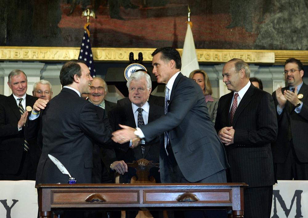 Massachusetts Gov. Mitt Romney, center right, shakes hands with Mass. Health and Human Services Secretary Timothy Murphy as Sen. Edward Kennedy, center; Mass. House Speaker Salvatore DiMasi, right, and others look on after signing into law a landmark bill designed to guarantee virtually all Massachusetts residents have health insurance on April 12, 2006. (AP)