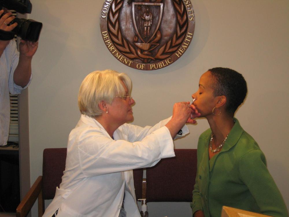 Mary Conant, a nurse at the state Department of Public Health, vaccinates state medical director Lauren Smith against the H1N1 virus using a nasal spray vaccine. (Sacha Pfeiffer/WBUR)