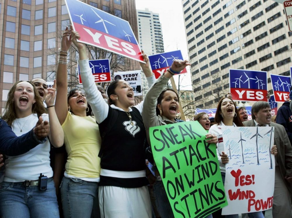 Advocates for the Cape Wind project hold signs outside Faneuil Hall in Boston in April 2006, where top state leaders were gathered for a bill signing. (AP)