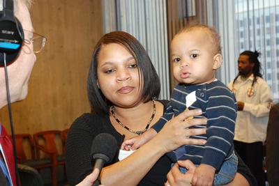 Sherry Atkins, Harvey's girlfriend, holds their son as she talks to WBUR's David Boeri. (Jesse Costa/WBUR)