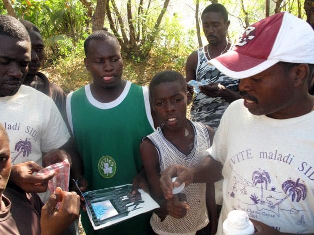Jean Magloire, right, distributes basic medical supplies gathered by a Christian prayer group from Roslindale. The most popular item in his plastic crate is ibuprofen. (Seth Rolbein for WBUR)