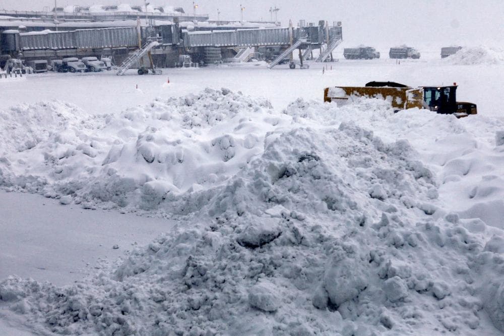 A snow plow is dwarfed by a pile of snow during snow cleanup on the tarmac at Washington's Reagan National Airport, Saturday, as a massive snow storm has hit the Washington area. (AP Photo/Jacquelyn Martin)