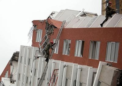 Firefighters search for victims in a collapsed building in Concepcion, Chile on Monday. (AP)