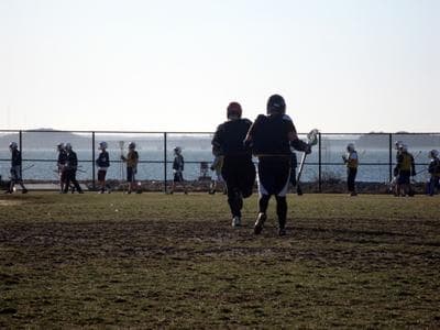The boys varsity lacrosse team holds its first outdoor practice of the year at Hull High School.  The team receives no money from the school’s athletic budget — because there isn’t one. (Fred Thys/WBUR