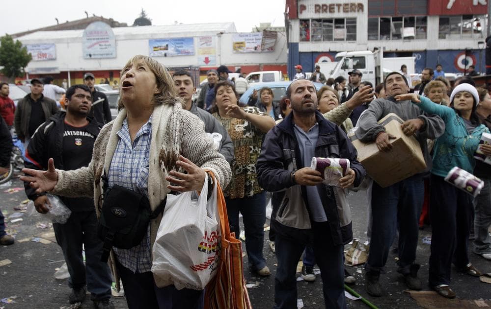 People wait to catch goods thrown from a supermarket window during sporadic looting in Concepcion, Chile following Saturday's earthquake (AP)