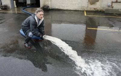 Manuel Rei, a building maintenance supervisor at Builders Surplus in West Warwick, R.I., pumps floodwater from the building. (AP)