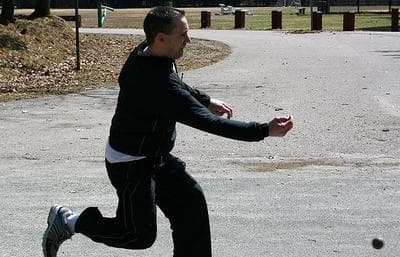 Competitor Pat Nee launches the bowl down the road on the Milton-Canton border.  As spring returns to Greater Boston, so too does Irish road bowling. (Chris Berdik for WBUR)