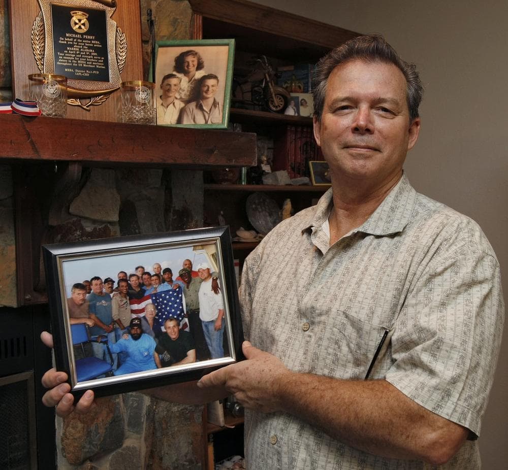 Michael Perry, 61, chief engineer of the Maersk Alabama, poses with a photo of the cargo ship's crew at his home in Riverview, Fla on Nov. 24, 2009. Perry blames Capt. Richard Phillips for the April 2009 hijacking of the ship. (AP)