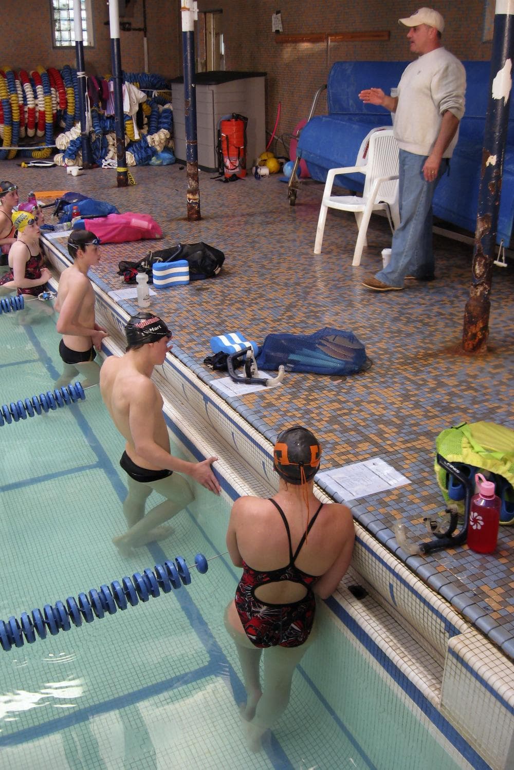 Coach Don Lemeiux instructs his team in front of the rusty posts that support the almost 100-year old swimming pool at the Greenwood Memorial Swim Club. (David Boeri/WBUR)