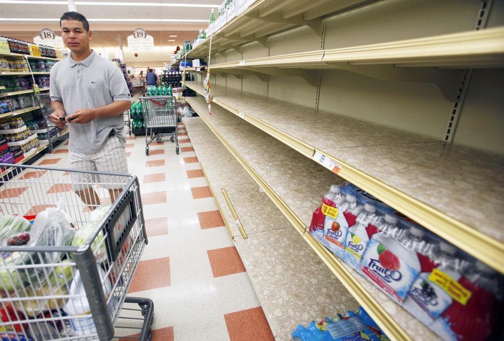 A man shops next to shelves emptied of bottled water Sunday at a supermarket in Chelsea. (AP)