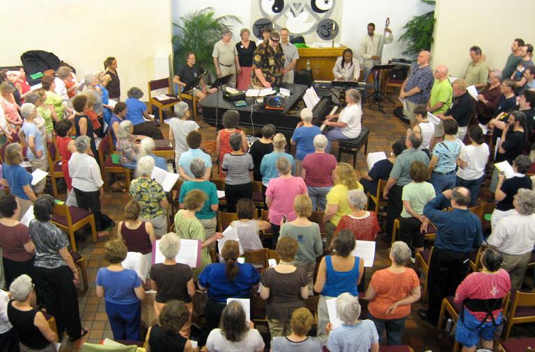 Founder Nick Page (center, behind the piano) leads his Mystic Chorale through a recent "sing" in Arlington. (Andrea Shea/WBUR)