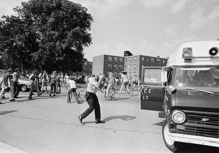 A policeman ducks for cover as a barrage of stones falls around him during an anti-busing protest in Boston in September 1974. (AP)