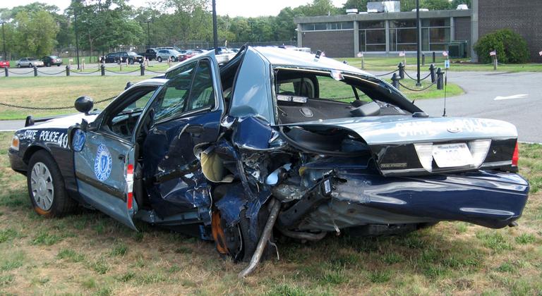 State Police spoke Thursday in front of Trooper Corey Rose's damaged cruiser. He was struck while pulled over on Route 24 in Taunton last weekend. (Curt Nickisch/WBUR)