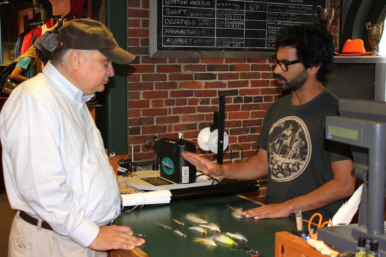 Stephen England, right, helps WBUR's Bob Oakes select the right fly for fishing Boston Harbor. (Lisa Tobin/WBUR)