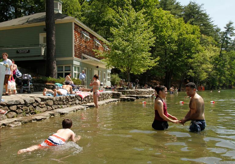 Betsy Rivera, second from right, and Halil Yumus, right, both of Boston, hold hands as they enter the water at Walden Pond, in Concord, Mass., in May. (AP)