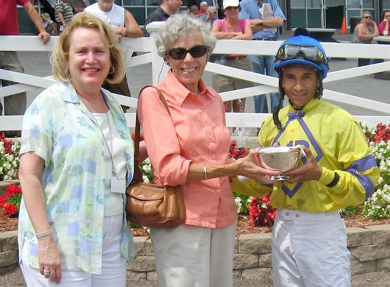 Former Olympian Imogene Fish, center, presents the North Hill Bowl to jockey Carlos Quinones. (Bill Littlefield/WBUR)