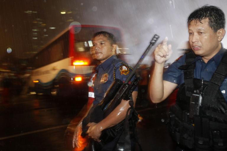 Police and SWAT members secure the scene following an assault on a tourist bus with foreign tourists taken hostage by a dismissed police officer at Manila's Rizal Park Monday, Aug. 23, 2010 in Manila, Philippines. Philippine police stormed the bus Monday evening after shots were heard from the hostage-taker of 15 Chinese tourists, and at least four of the hostages crawled out of the back door. (AP Photo/Bullit Marquez)