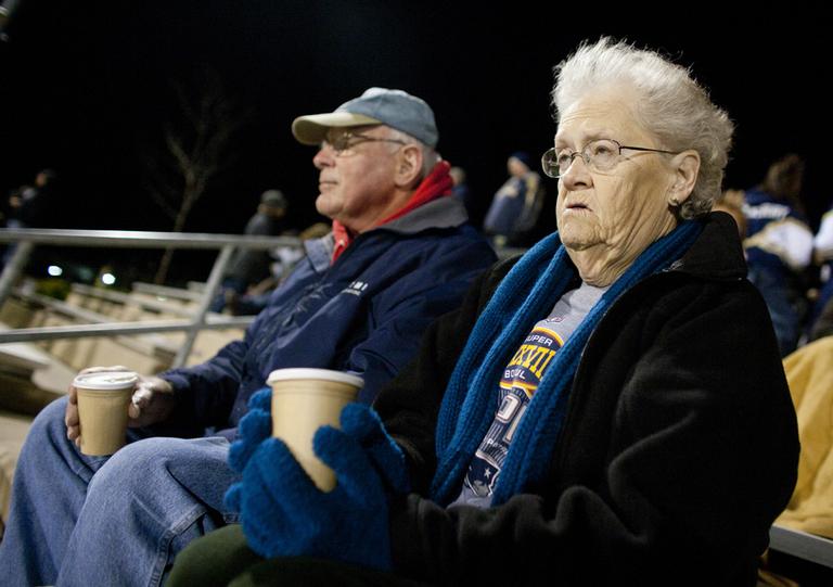 Bill and Frances Theis keep warm with hot cocoa and wait for their grandson to take the field after halftime at a Shrewsbury Senior High School football game. (Dominick Reuter for WBUR)