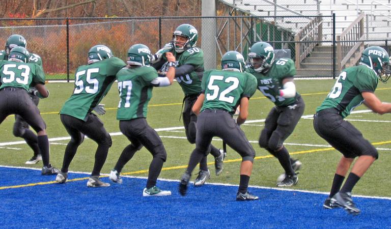 The Post University squad warms up before its game with Mansfield. In sprint football, linemen often have to learn the position from scratch because they were small played “skill” positions, like wide receiver, on their high schools’ regular football teams. (Photo by Doug Tribou)