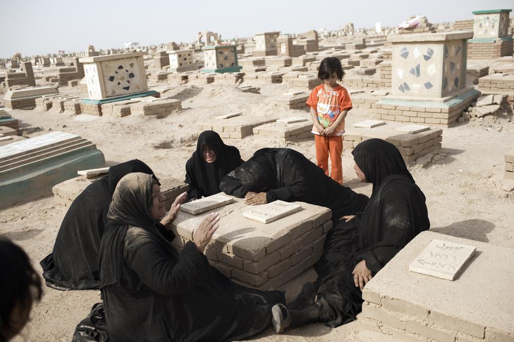Relatives of Mohamad Jassim, grieve by his grave in the Wadi al-Saalam cemetery in Najaf.   Mohamad disappeared from his neighborhood in Baghdad in 2005, but it was years later that the Jassim family received news of his fate after recognizing the photograph of his body. (Photo by Moises Saman for The New York Times)                              
