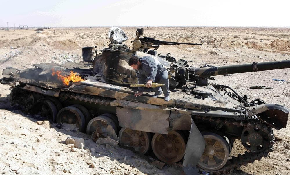 A Libyan rebel carries a rocket-propelled grenade as he jumps from a destroyed Libyan tank in the city of Ajdabiya, south of Benghazi, eastern Libya, Saturday. (AP)