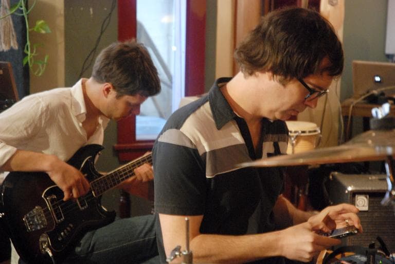 OK Go's Damian Kulash, left, and Ben Folds participate in an experiment to record eight songs in eight hours to illustrate the immediacy of the music world these days. They also asked their fans to tweet song titles as they recorded (hence Folds on the phone). (Andrea Shea/WBUR)