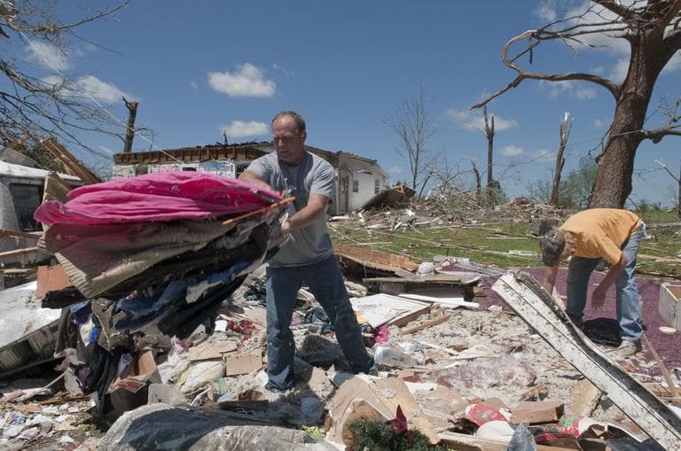 Mark Plunkett, left, with the help of Allen Southerland, right, find some of his wife's clothing in the debris of his Phil Campbell, Ala., home Thursday. (AP)