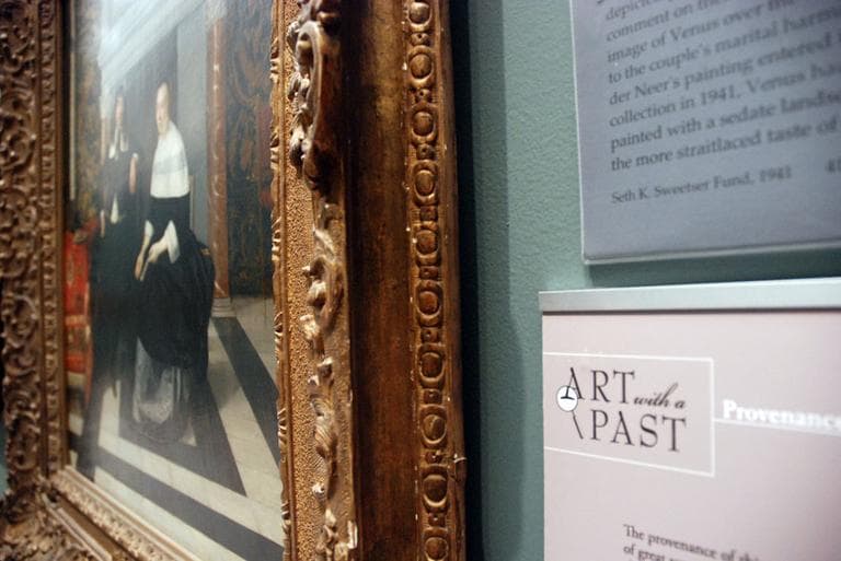 The 17th century Dutch painting "Portrait of a Man and a Woman in an Interior" with a panel about its history at Boston's Museum of Fine Art (Meghna Chakrabarti/WBUR)