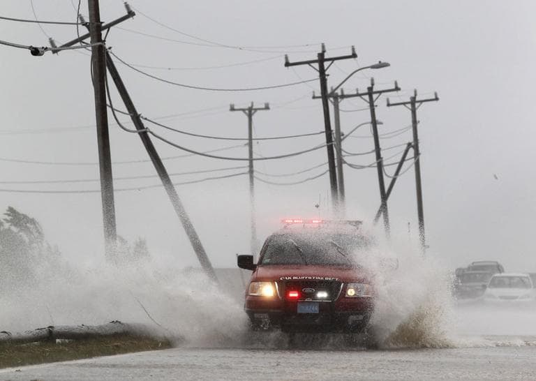 An Oak Bluffs Fire Department vehicle is buffeted by strong winds and ocean spray from Tropical Storm Irene while driving along a costal road in Edgartown Sunday. (AP)