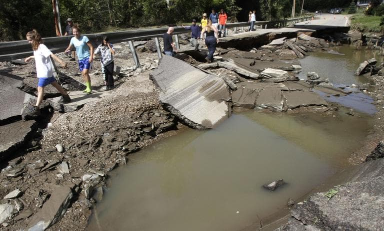 People walk along a washed out section of Route 12 in Berlin, Vt., Monday. (AP)