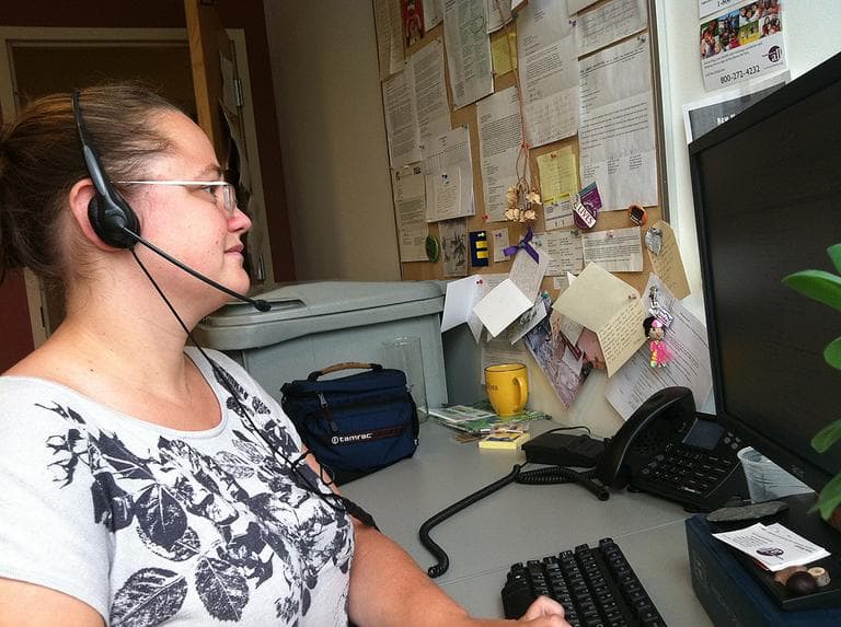 Kate Bicego talks to callers who need health coverage at Health Care For All. (Martha Bebinger/WBUR)