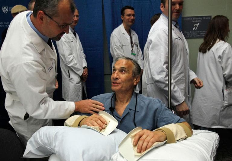Double hand transplant recipient Richard Mangino smiles as he is patted on the shoulder by Dr. Bohdan Pomahac, director of plastic surgery transplantation at Brigham And Women's Hopsital, following a news conference Friday. (AP)