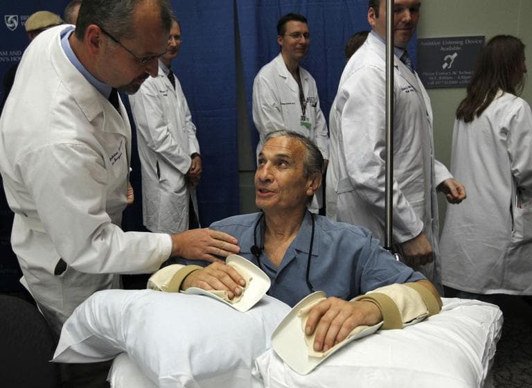 Double hand transplant recipient Richard Mangino, 65, of Revere, Mass., bottom, smiles as he is patted on the shoulder by Dr. Bohdan Pomahac, director of plastic surgery transplantation at Brigham Women's Hopsital, in Boston, Oct. 14. (AP)