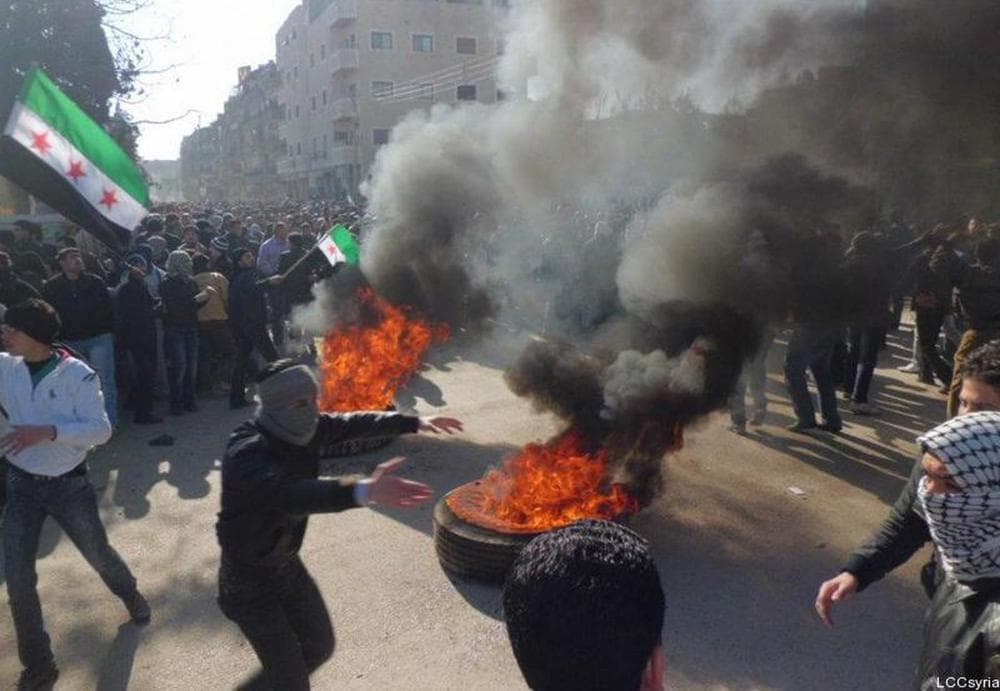 Committees in Syria, anti-Syrian regime protesters, burn tires and wave Syrian revolution flag during a demonstration in the suburb of Daraya, Damascus, Syria, on Saturday Feb. 4, 2012. (AP)