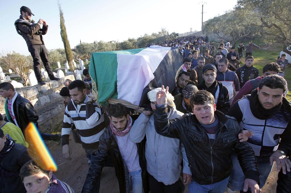 Anti-government protesters carry the coffin of a slain protester, draped in the revolutionary flag, during the funeral of two comrades killed in earlier clashes in Idlib, north Syria. (AP)
