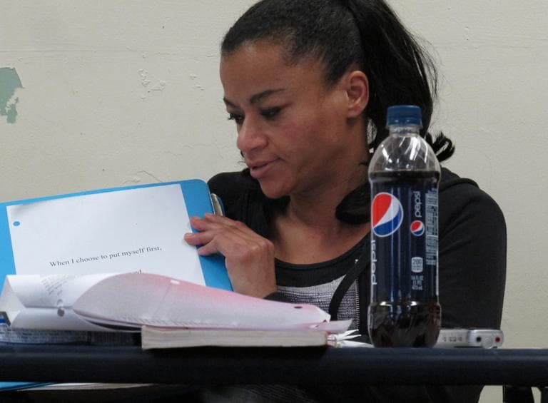 Christina Mondesir, 36, holds up her binder with a quote that reads "When I choose to put myself first, all others are served." (Andrea Shea/WBUR)