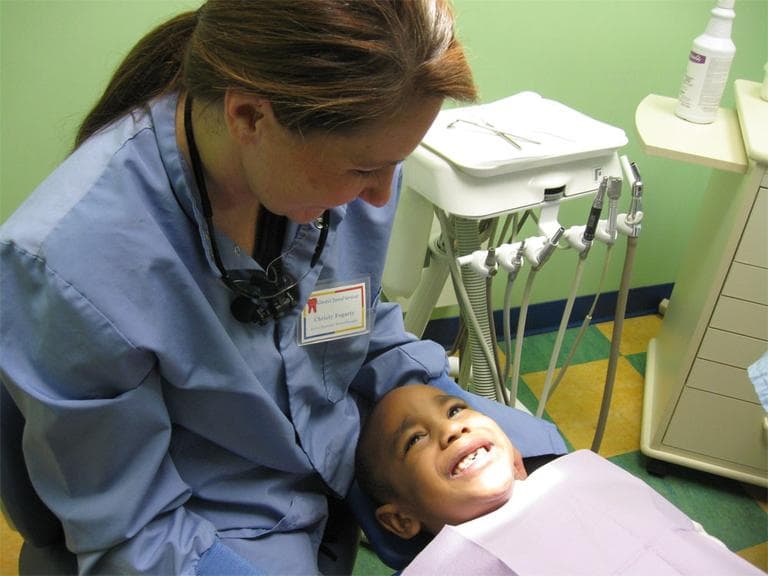 Dental therapist Christy Jo Fogarty gets ready to examine Valentino Cotten in Minneapolis, Minn. (Sasha Aslanian/Minnesota Public Radio)