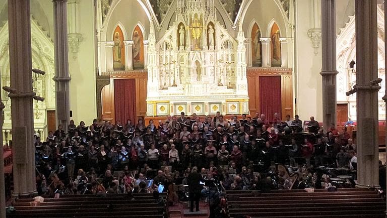 Richard Pittman directs 300 musicians during a rehearsal of "War Requiem" at the Cathedral of the Holy Cross. (Meghna Chakrabarti/WBUR)
