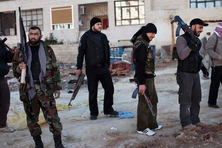 Free Syrian Army fighters gather near a building hit by a Syrian Army tank in Idlib, north Syria on Sunday. (Rodrigo Abd/AP)