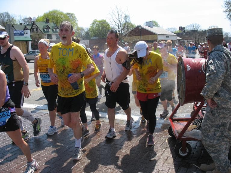 In Wellesley, marathon runners enjoy one of the many mist stations set up along the marathon route. (Martha Bebinger/WBUR)