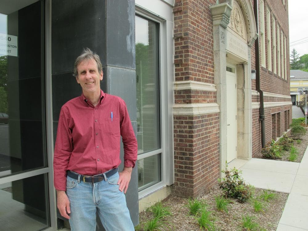 Kevin Carragee, of the Presentation Foundation Board, stands beside a wall of old chalkboards that have been incorporated into the new building. (Monica Brady-Myerov/WBUR)
