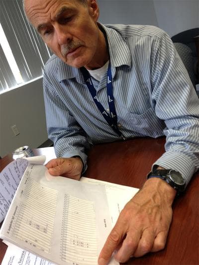 Dr. Philip Molloy reviews a western blot test at Imugen, a lab in Norwood. (Martha Bebinger/WBUR)